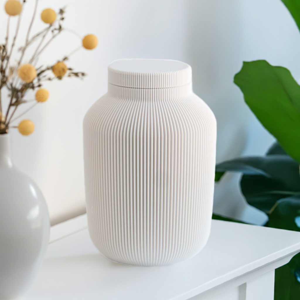 Willow cremation urn in white with modern vertical sculpted texture, displayed on a white table with decorative greenery.