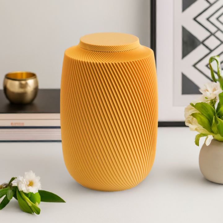 Mustard Aspen cremation urn with contemporary spiral sculpted design, styled with flowers and warm decorative accents.