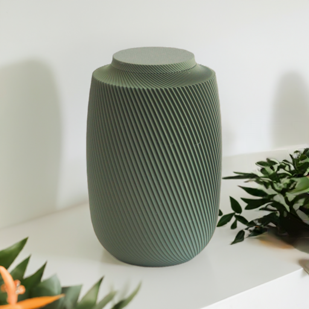 Aspen cremation urn in green with modern sculpted texture, displayed on a white surface with greenery.